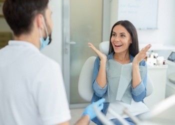 Woman in dental chair grinning at her dentist