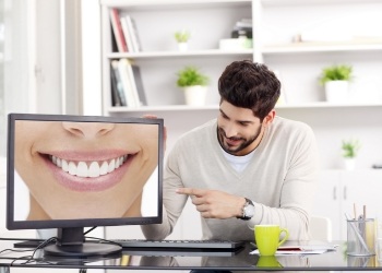 Man pointing to computer monitor showing smile with flawless teeth