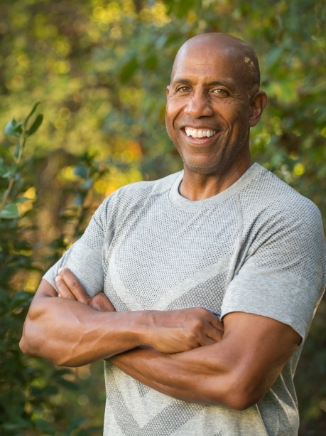Man in gray tee shirt smiling outdoors with dental bridges in Gorham
