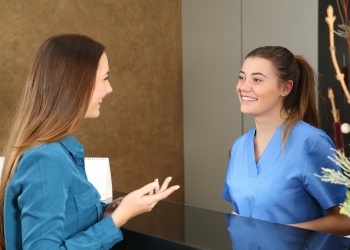 Woman talking to dental team member at front desk