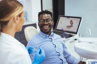 Man in dental chair smiling at his dentist