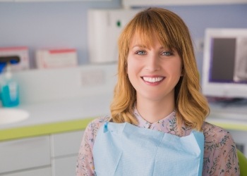 Woman with orange hair smiling in dental chair