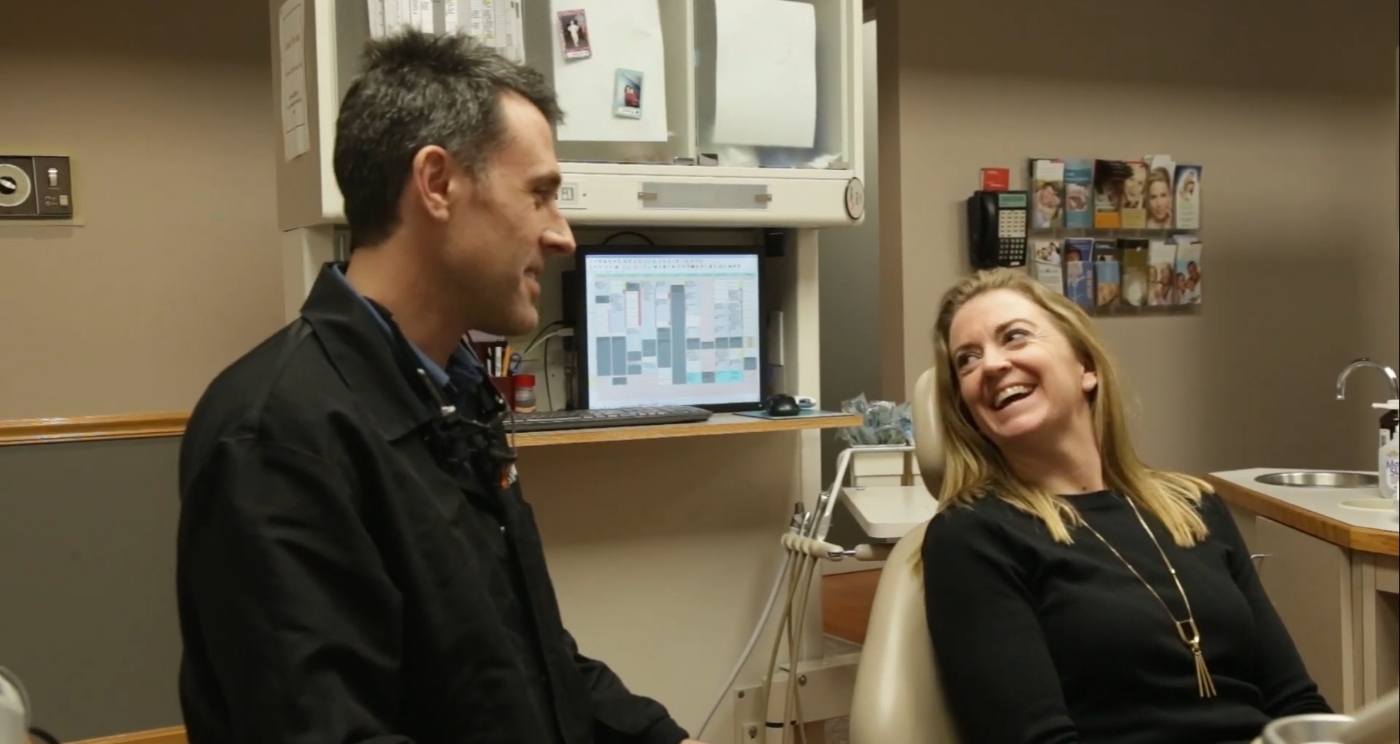Doctor Brett talking to a woman in the dental chair