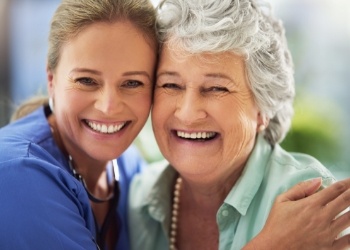 Two women smiling and hugging side by side