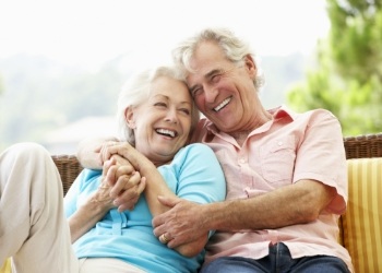 Senior man and woman laughing and sitting outdoors together