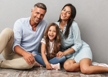 Smiling family of three sitting on floor