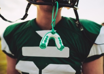 Football player with mouthguard hanging from their helmet