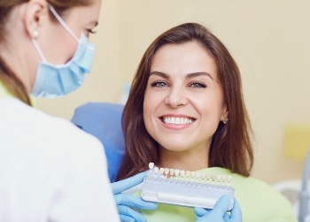 Woman in dental chair smiling while getting veneers