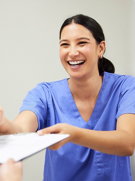 a dental assistant handing a patient forms