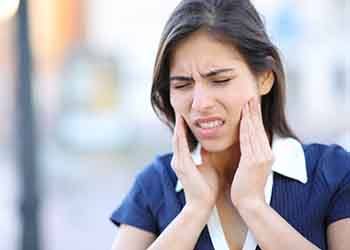 Woman in blue shirt outside with jaw pain