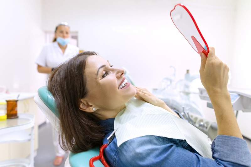 Patient smiling at their new dental crown in the mirror